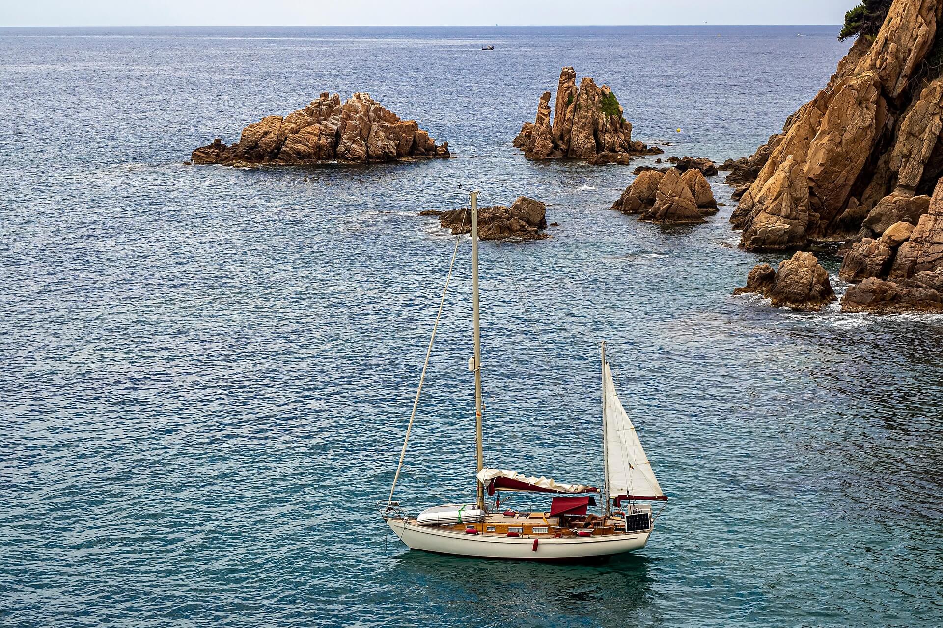 Aerial view of a Costa Brava cove with turquoise water and pine-covered cliffs